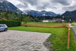 A residential area with a paved driveway, a car, a wooden fence, and a building with a flat roof. - Holiday apartment with 3 bedrooms (Wald im Pinzgau)