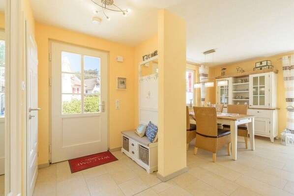 A bright room with a door, a bench, a dining table with chairs, and a kitchen area with cabinets and a refrigerator. - Holiday home in Glowe with swimming pool (Glowe)
