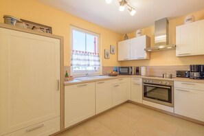 A kitchen with white cabinets, a microwave, an oven, and a sink. - Holiday home in Glowe with swimming pool (Glowe)
