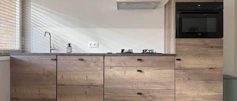 A modern kitchen with wooden cabinets, a stainless steel range hood, and a built-in microwave.