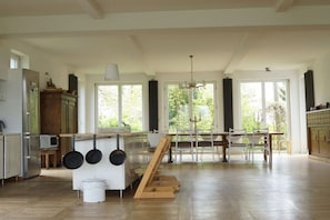 A spacious kitchen with a dining area, large windows, and a chandelier.