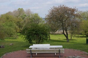 A park bench in a grassy area with trees and a clear sky.