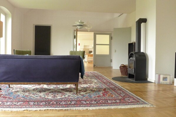 A living room with a sofa, a patterned rug, a fireplace, and a view into another room. - Cabin in Nordwestuckermark with sauna (Nordwestuckermark)