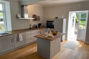 A kitchen with a central island, a built-in oven, and a refrigerator. - Stintenburg Island: Bridge House (Zarrentin am Schaalsee)