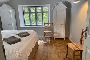 Ein Schlafzimmer mit einem Bett, zwei Stühlen, einem Fenster und einem Kleiderschrank.