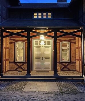 A building with a covered entrance, a central door, and two windows on either side. - Stintenburg Island: Bridge House (Zarrentin am Schaalsee)