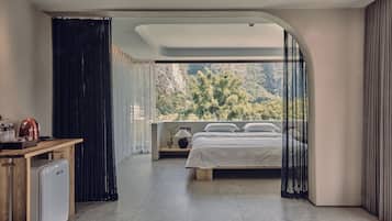 Un dormitorio moderno con cama, mesita de noche y vista a un área boscosa.