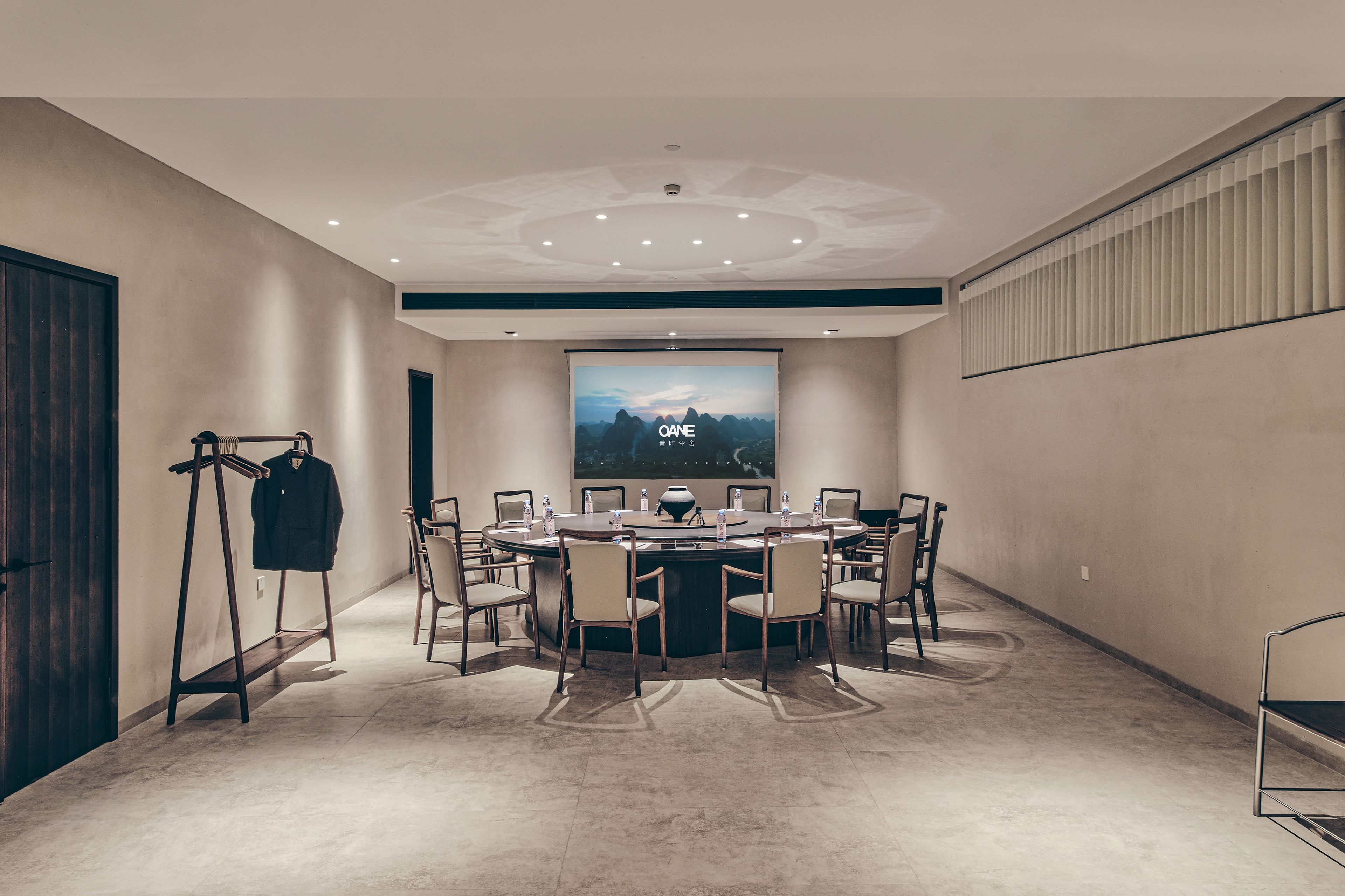 A conference room with a large screen, round table, and chairs.