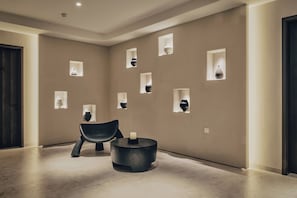 A modern interior with a minimalist design, featuring a dark wooden door, a black chair, a round table, and several wall-mounted light fixtures. - Yangshuo Yulong Riverfront Resort - Xishi Jinshe (Guilin)