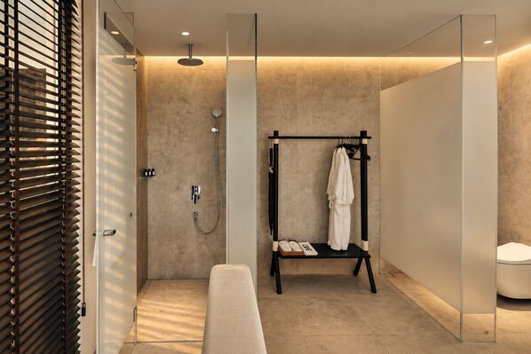 A modern bathroom with a walk-in shower, a bench, and a towel rack.