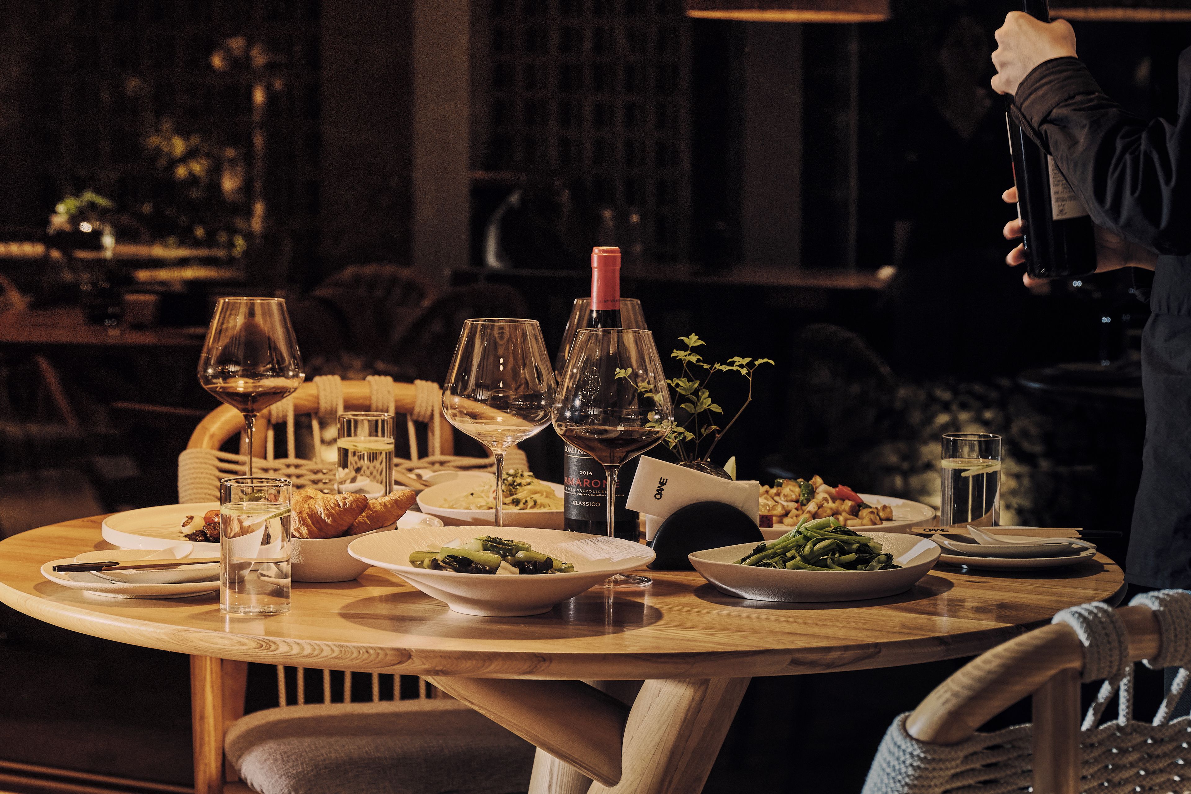 A dining table set with plates of food, glasses, and a bottle of wine, suggesting a restaurant setting.