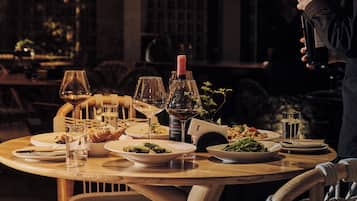 A dining table set with plates of food, glasses, and a bottle of wine, suggesting a restaurant setting.