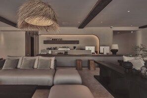 A modern living room with a sofa, a coffee table, and a dining area with a bar.