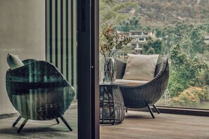 A modern outdoor seating area with wicker furniture and a view of a hillside.