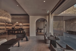 A modern interior with a dining area, seating arrangements, and a view through a large window.