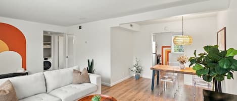 A modern living room with a sofa, coffee table, and dining area with chairs.
