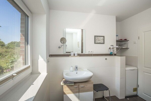 A bathroom with a white sink, a mirror, and a window. - View of the Schlei shore (Bohnert)