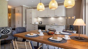 Une cuisine moderne avec un coin repas, comprenant une table en bois, des chaises et des luminaires suspendus.
