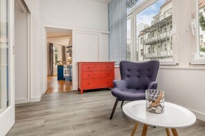 A room with a modern design, featuring a grey upholstered armchair, a white round table, and a red dresser. - Baltic Sea view in the Villa Stranddistel (Binz)