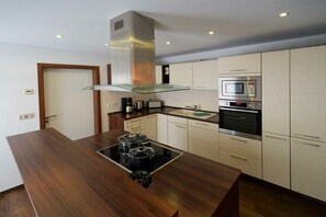 A modern kitchen with a central island, built-in oven, microwave, and stainless steel range hood. - Holiday apartment with 3 bedrooms (Lübbenau)