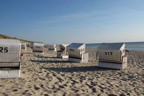 Bungalôs de praia numerados 25, 613, 641, 643, 317 e 734 numa praia de areia.