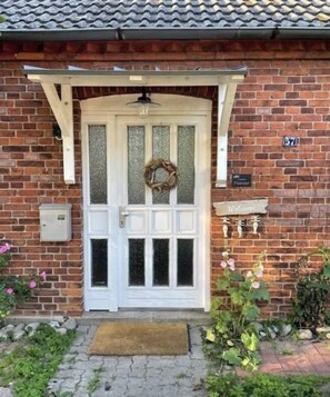 A brick building with a white door, a welcome sign, and a mailbox. - country house style in Heiligenhafen (Heiligenhafen)