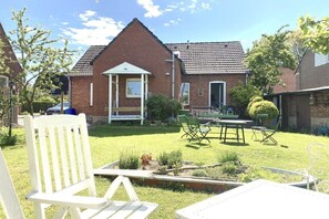 A residential property with a brick house, a covered porch, a lawn, and outdoor furniture. - country house style in Heiligenhafen (Heiligenhafen)