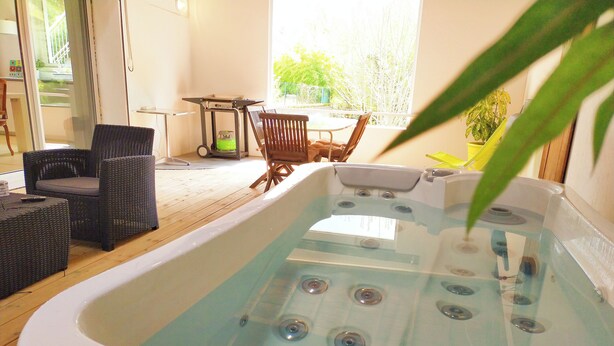Un jacuzzi con terraza de madera, mobiliario de mimbre y vistas al exterior.