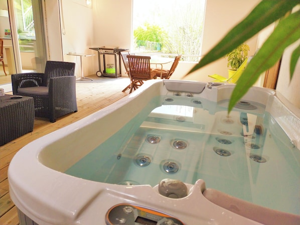 Un jacuzzi con terraza de madera, mobiliario de mimbre y vistas al exterior.
