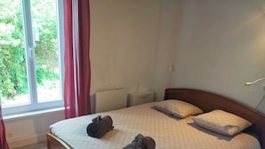Un dormitorio con una cama, dos almohadas y dos toallas enrolladas.