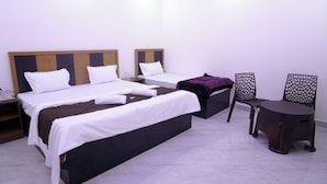 Een hotelkamer met twee bedden, een tafeltje en twee stoelen.