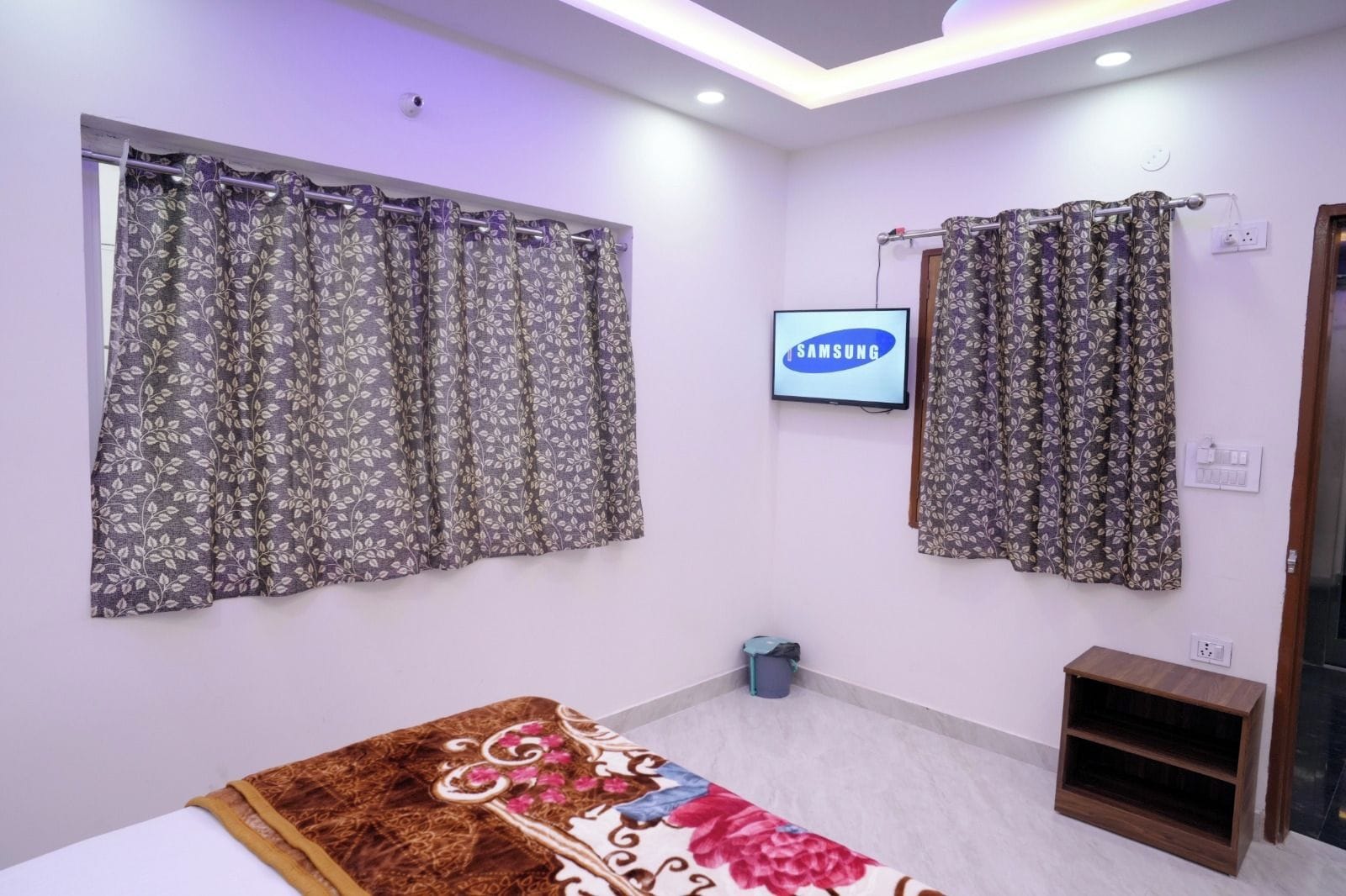 A hotel room with a bed, a TV, and curtains.