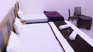 Een hotelkamer met twee bedden, een kleintje tafeltje met een dienblad glazen, en een stoel.