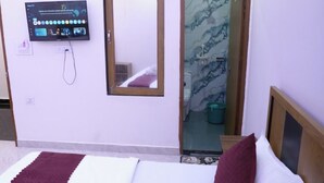 Een hotelkamer met een bed, een aan de muur bevestigde televisie, een spiegel en een deur naar een badkamer.