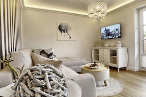 Ein modernes Wohnzimmer mit einer Couch, einem runden Couchtisch und einem an der Wand befestigten Fernseher.
