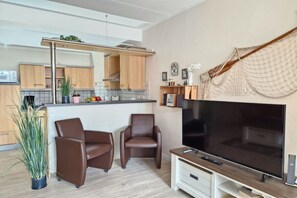 Eine moderne Küche mit Holzschränken, einer zentralen Kochinsel und einem Flachbildfernseher.