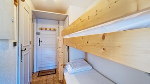 Un passadís estret amb un llit superposat de fusta a la dreta i una porta al final.
