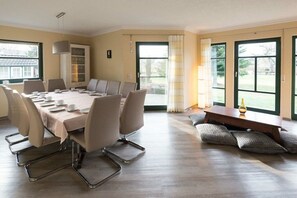 A conference room with a long table, chairs, and a small table with a vase. - Holiday home in Lübbenau with swimming pool (Lübbenau)