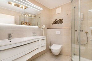 Ein modernes Badezimmer mit Duschkabine aus Glas, einer weißen Toilette und einem Waschtisch mit Schubladen.