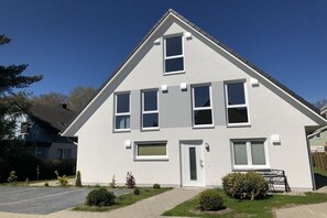 Uma casa moderna de dois andares, com fachada simétrica, porta central e pequeno jardim frontal.