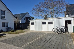 Une cour pavée où est garé un vélo, près d’un bâtiment doté de deux portes de garage.