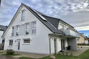 A modern two-story house with a sloped roof, a balcony, and a small front yard. - Holiday apartment with 2 bedrooms (Zinnowitz)