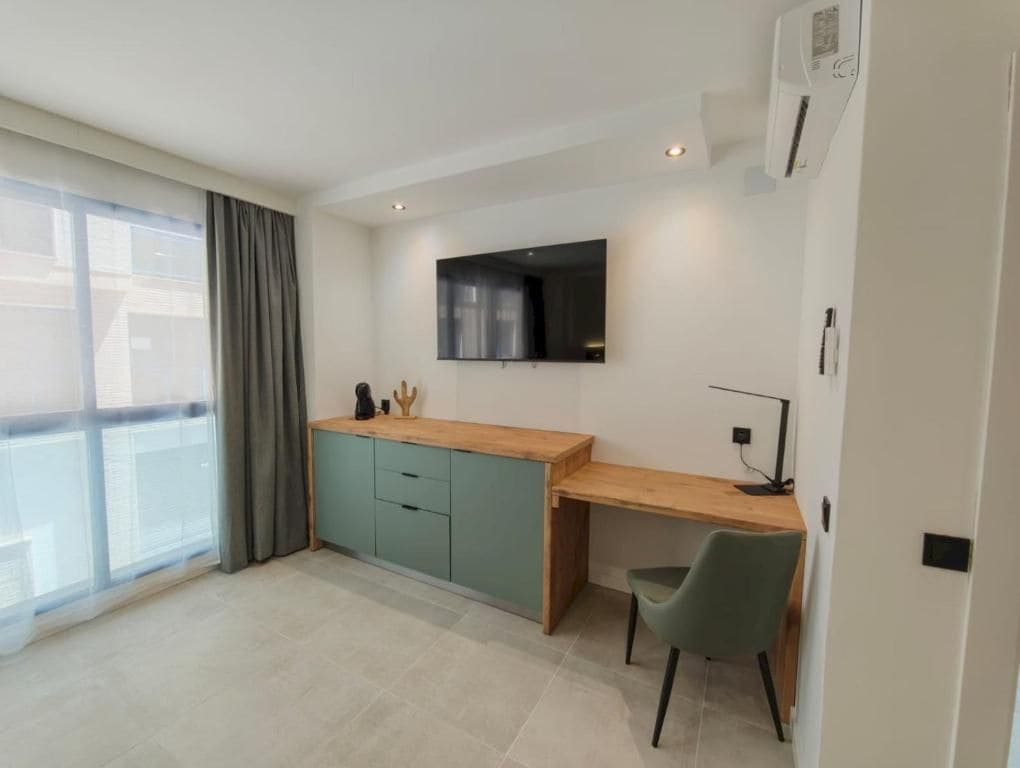 Una cocina moderna con encimera de madera, armarios verde azulado y estufa integrada.