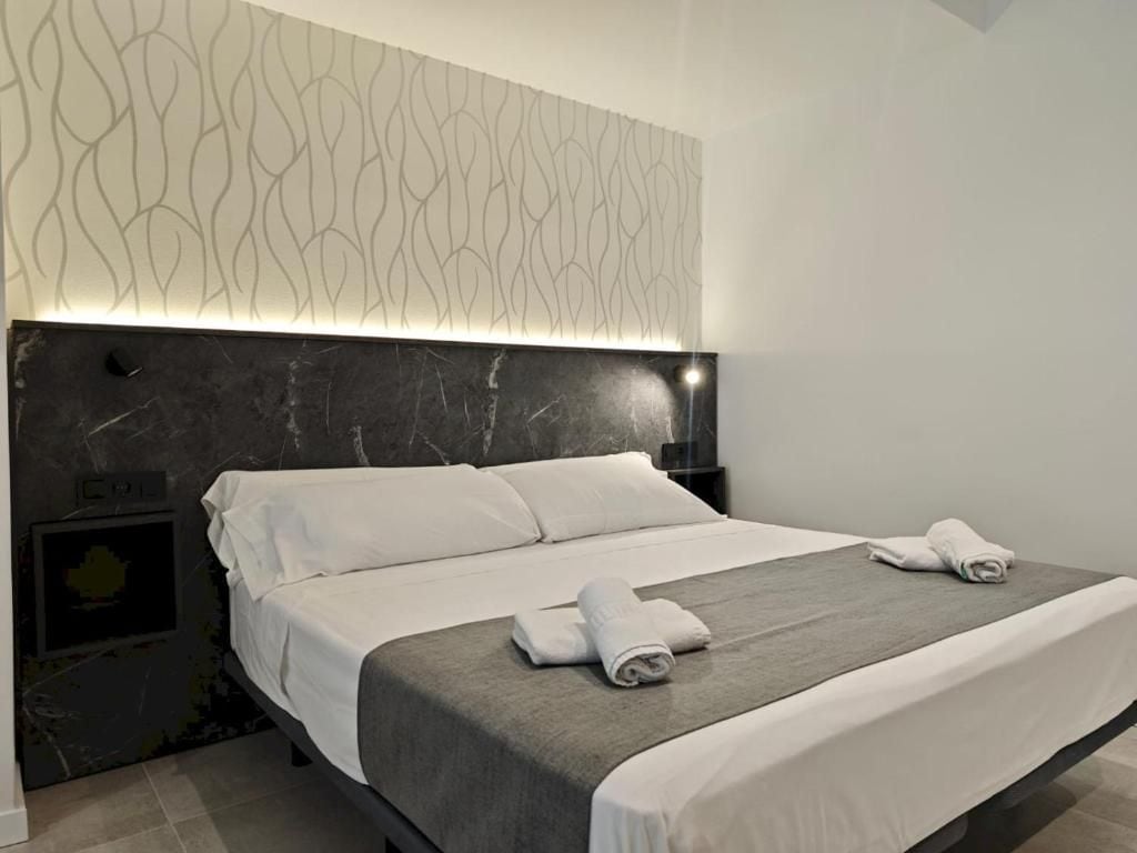 Een moderne hotelkamer met een groot bed, een hoofdeinde met een uniek patroon en een nachtkastje met een lamp.