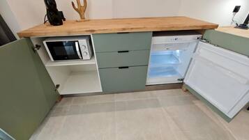 Cozinha equipada com micro-ondas, geladeira e bancada de madeira.