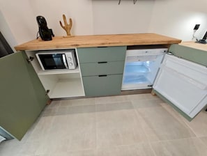 A kitchen with a microwave, a refrigerator, and a wooden countertop. - AH RENTALS Smart Living (Vinaròs)