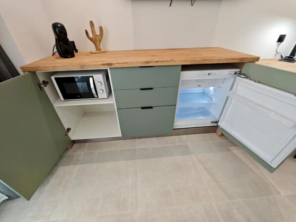 Una cocina con microondas, refrigerador y encimera de madera.