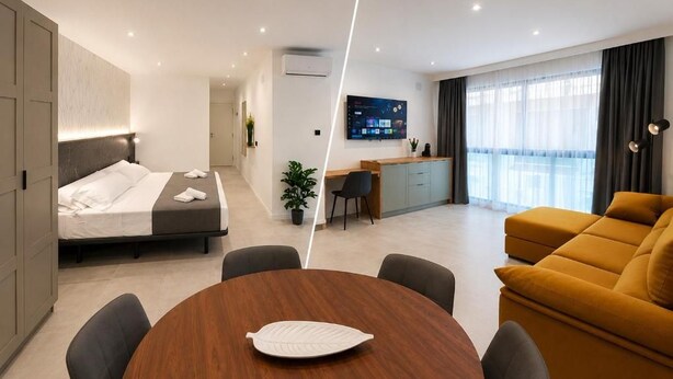 Quarto de hotel moderno com cama, mesa de jantar com cadeiras, sofá, escrivaninha com cadeira e televisão na parede.