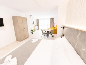 Una habitación de hotel con cama, escritorio, silla, sofá y armario.