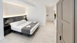 Quarto moderno com cama, mesas de cabeceira e guarda-roupa.